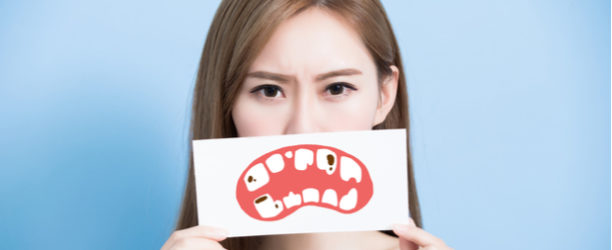 girl with sign over her mouth showing cavities